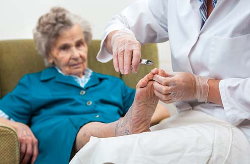 elderly woman having her toenails trimmed by a professional
