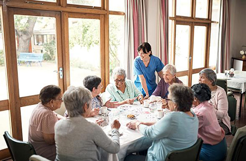 health care professional standing at a table of seniors in a dining room
