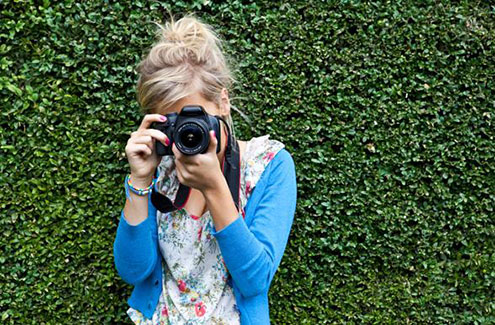 a woman holding a digital camera up to her face to take a picture