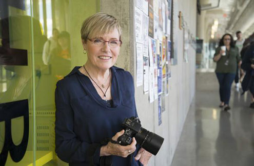 female photographer standing in a hallway with a camera