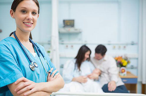 Nurse posing in front of family with newborn