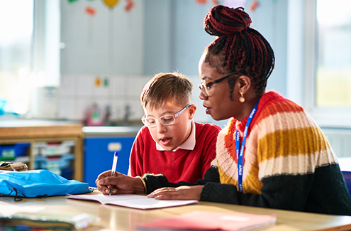 an adult working with a child in a classroom