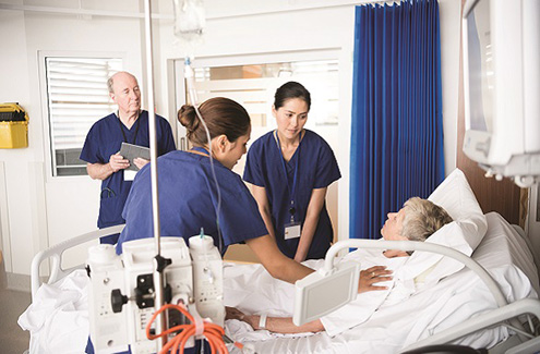 Three professionals around a patient's bed.