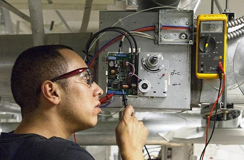 man wearing safety glasses working at a building systems machine